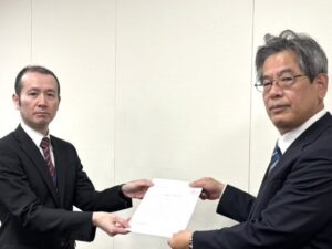 北浦参事官補佐に要求書を提出する香月事務局長（右）